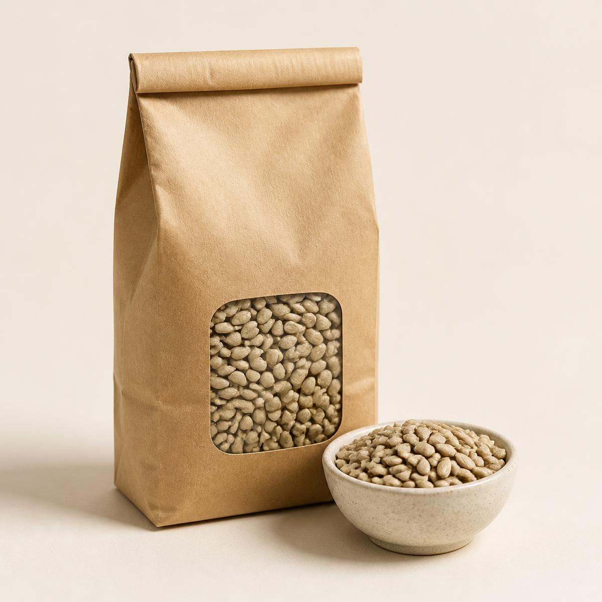Kraft sack with window showing hulled sunflower hearts beside a small stoneware bowl